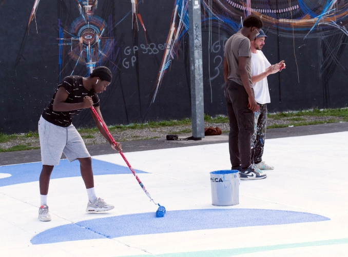 Un jeune de l'Académie Younus participe à la rénovation d'un terrain de baskteball dans le quartier du Grand Parc à Bordeaux.