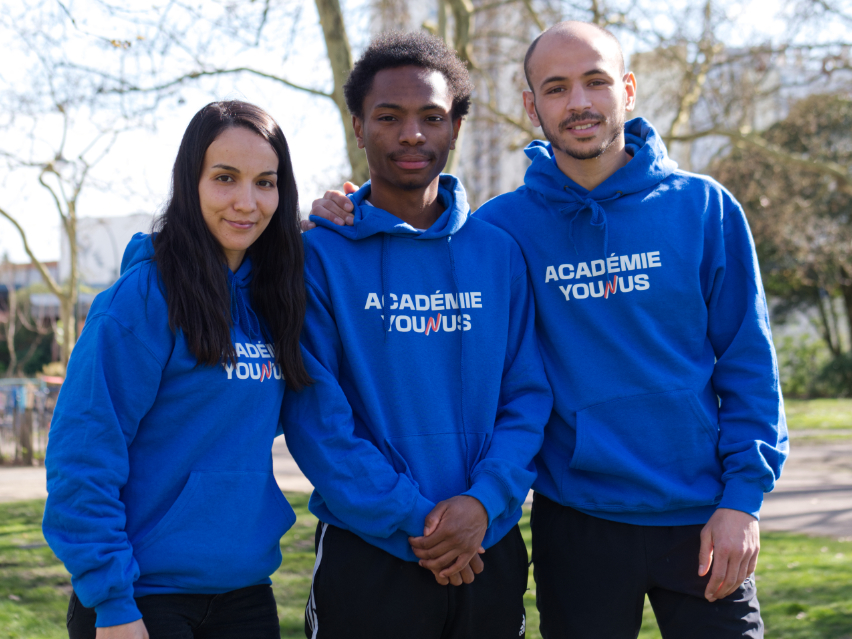 Deux salariés de l'Académie Younus prennent la pose avec un volontaire en service civique dans le quartier du Grand Parc à Bordeaux.